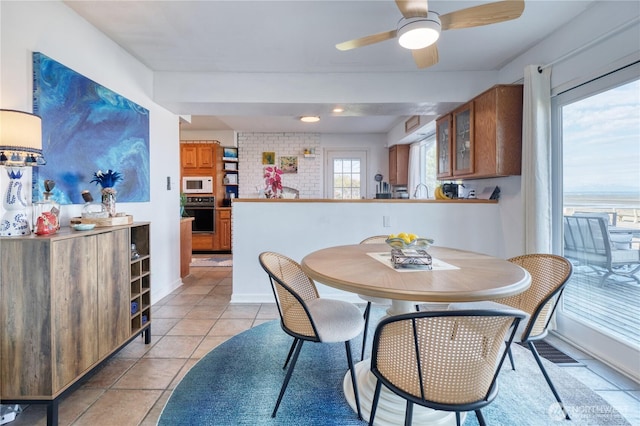 dining area with light tile patterned floors, a ceiling fan, and baseboards