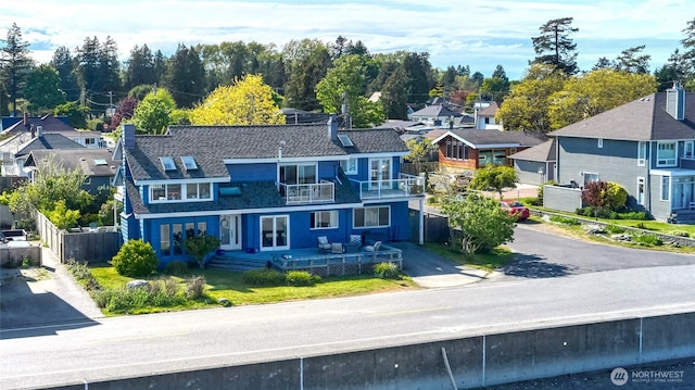 view of front of house with a balcony, a residential view, and fence