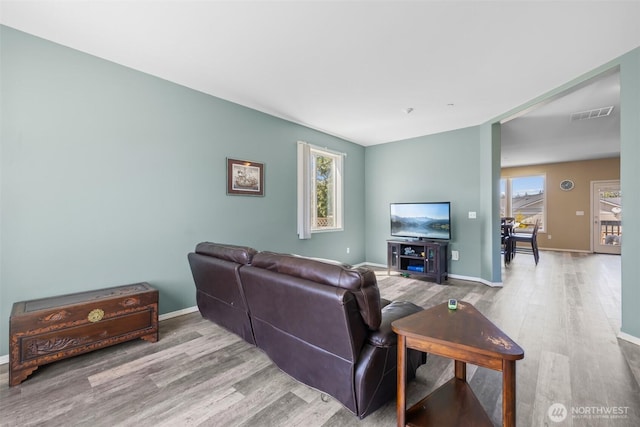 living room with wood finished floors, plenty of natural light, and baseboards
