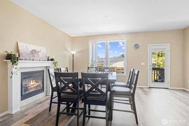dining area featuring wood finished floors, a fireplace, and baseboards