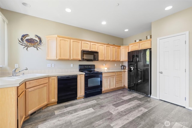 kitchen with black appliances, light brown cabinetry, a sink, light wood-style flooring, and recessed lighting