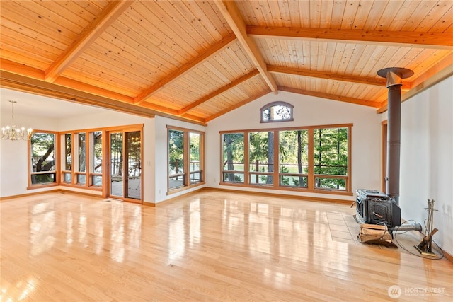 244 Davison Head Dr, Friday Harbor, WA 98250 - unfurnished living room featuring a wood stove, a chandelier, wood finished floors, beam ceiling, and baseboards