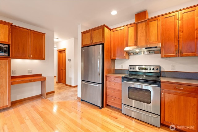 244 Davison Head Dr, Friday Harbor, WA 98250 - kitchen featuring stainless steel appliances, under cabinet range hood, brown cabinets, light wood finished floors, and baseboards