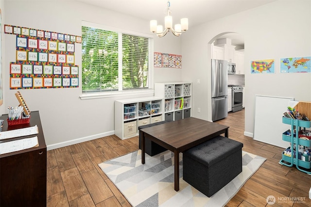 dining area with arched walkways, wood finished floors, a chandelier, and baseboards