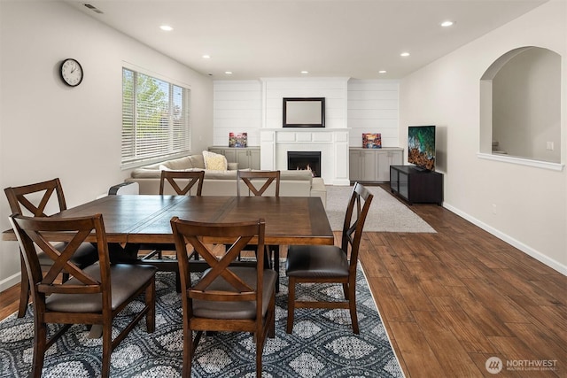 dining room with recessed lighting, dark wood-type flooring, baseboards, and a lit fireplace