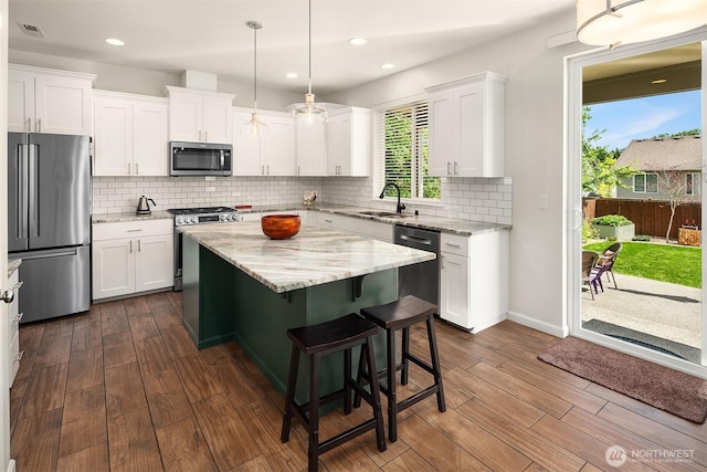 kitchen featuring stainless steel appliances, a center island, white cabinetry, dark wood-style flooring, and recessed lighting