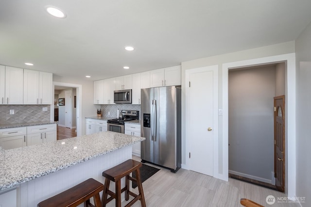 303 Patrick Rd, Ephrata, WA 98823 - kitchen featuring appliances with stainless steel finishes, a kitchen breakfast bar, backsplash, white cabinets, and light stone counters