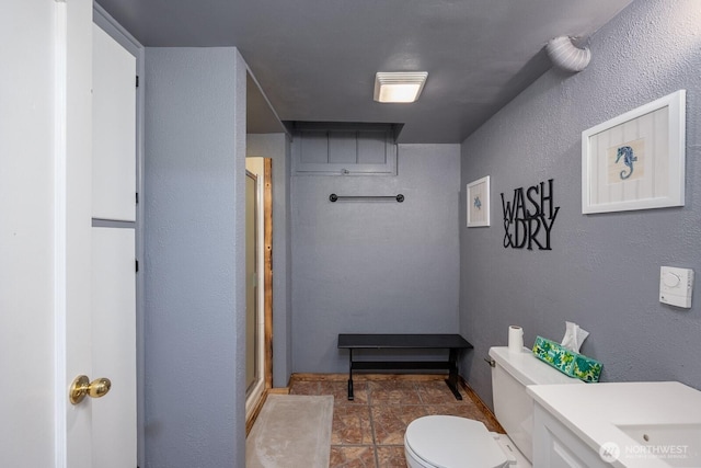 303 Patrick Rd, Ephrata, WA 98823 - bathroom featuring a shower stall, toilet, a textured wall, stone finish flooring, and vanity