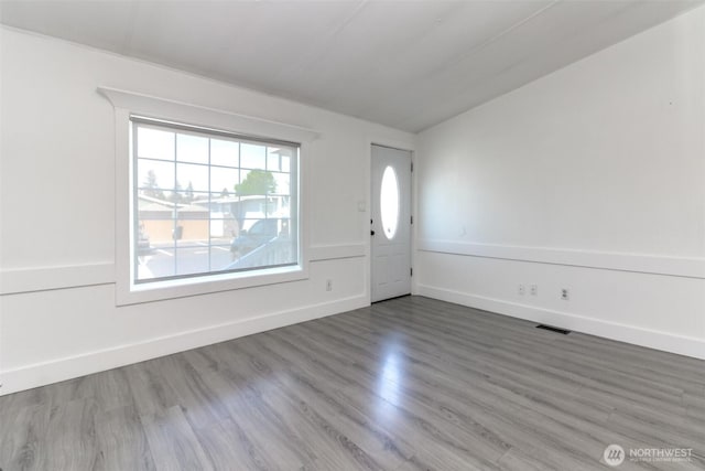 foyer featuring wood finished floors, baseboards, and vaulted ceiling