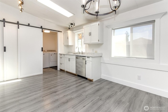kitchen featuring dishwasher, washer and dryer, a barn door, a chandelier, and white cabinetry