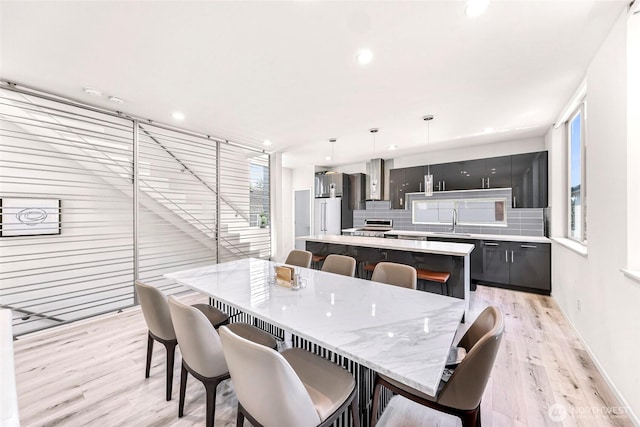 dining space featuring light wood-style flooring, plenty of natural light, recessed lighting, and baseboards