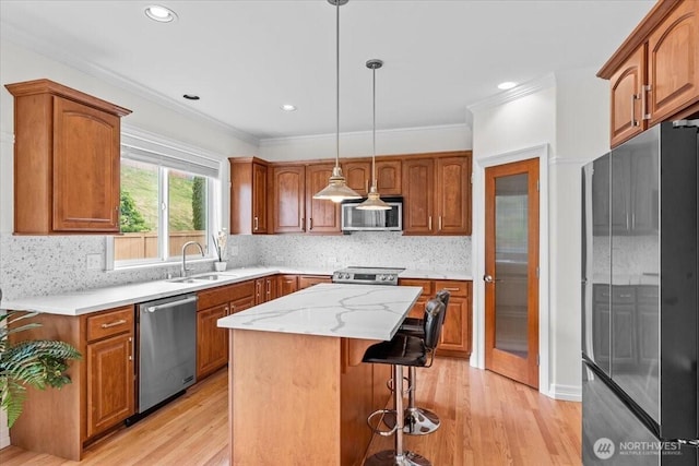 27546 254th Way SE, Maple Valley, WA 98038 - kitchen featuring appliances with stainless steel finishes, a sink, brown cabinetry, light wood-style flooring, and crown molding