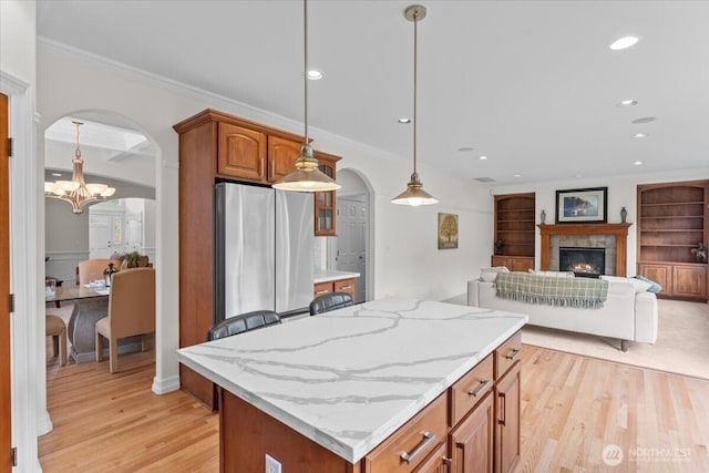 27546 254th Way SE, Maple Valley, WA 98038 - kitchen with arched walkways, a chandelier, light wood-style floors, a center island, and brown cabinets