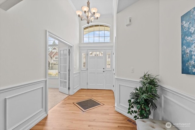 27546 254th Way SE, Maple Valley, WA 98038 - foyer entrance with wainscoting, a chandelier, a decorative wall, and wood finished floors