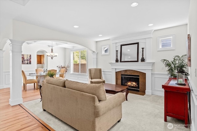 27546 254th Way SE, Maple Valley, WA 98038 - living room with arched walkways, a decorative wall, a chandelier, a high end fireplace, and wainscoting