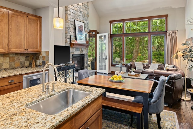 221 Cake Box Ln, Cle Elum, WA 98922 - kitchen with dark wood-type flooring, brown cabinetry, open floor plan, a stone fireplace, and light stone countertops