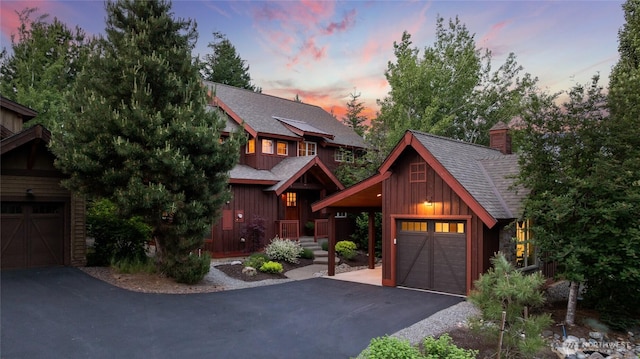 221 Cake Box Ln, Cle Elum, WA 98922 - chalet / cabin featuring board and batten siding, a shingled roof, asphalt driveway, a chimney, and a garage