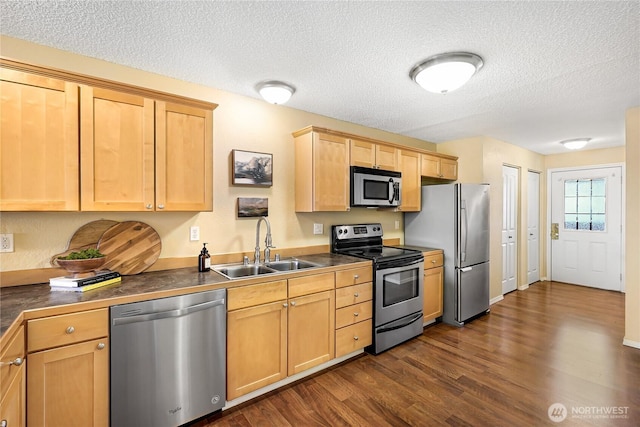 kitchen featuring stainless steel appliances, a sink, dark wood finished floors, dark countertops, and a textured ceiling