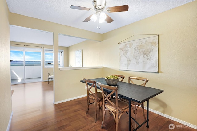 dining room featuring baseboards, wood finished floors, a ceiling fan, and a textured ceiling