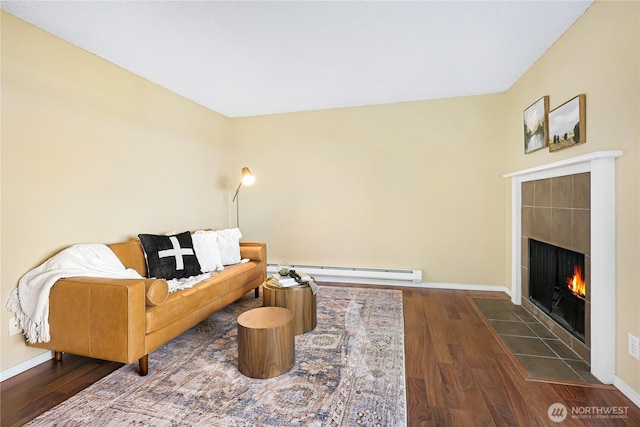 living area featuring a baseboard radiator, wood finished floors, a tile fireplace, and baseboards