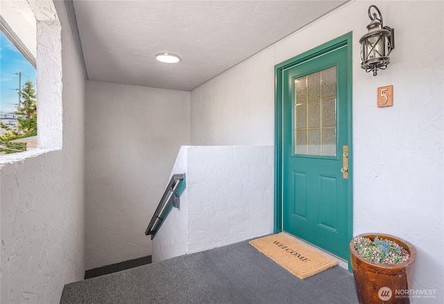 property entrance with stucco siding and a balcony