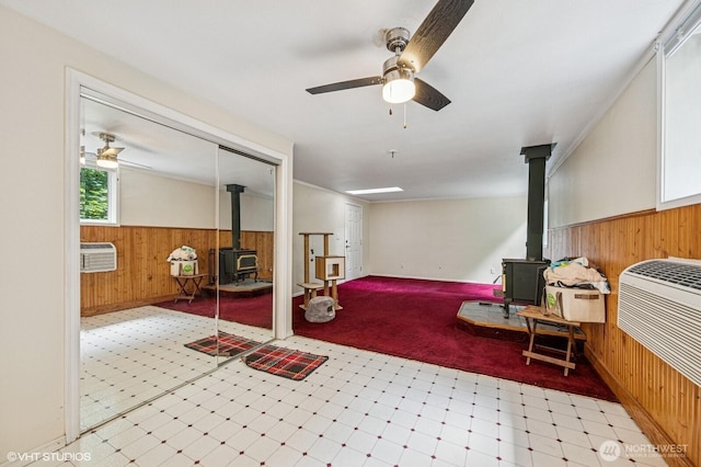 22434 SE Auburn-Black Diamond Rd, Black Diamond, WA 98010 - below grade area with a wood stove, wood walls, ceiling fan, tile patterned floors, and wainscoting