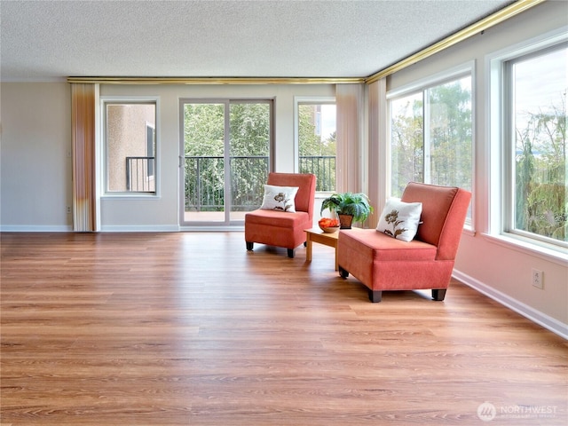 living area with crown molding, a textured ceiling, wood finished floors, and baseboards