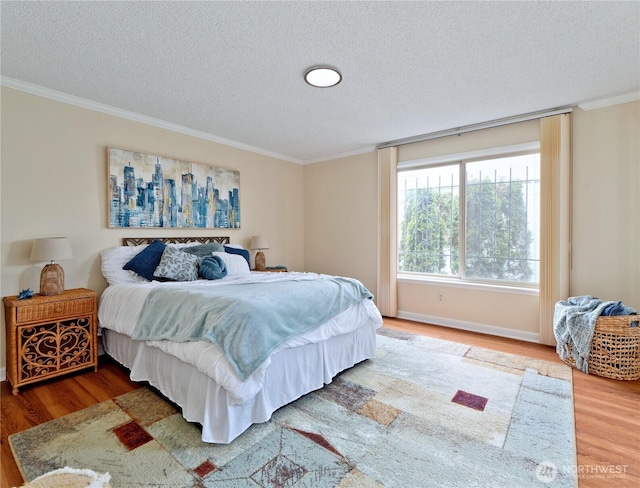 bedroom with wood finished floors, crown molding, a textured ceiling, and baseboards