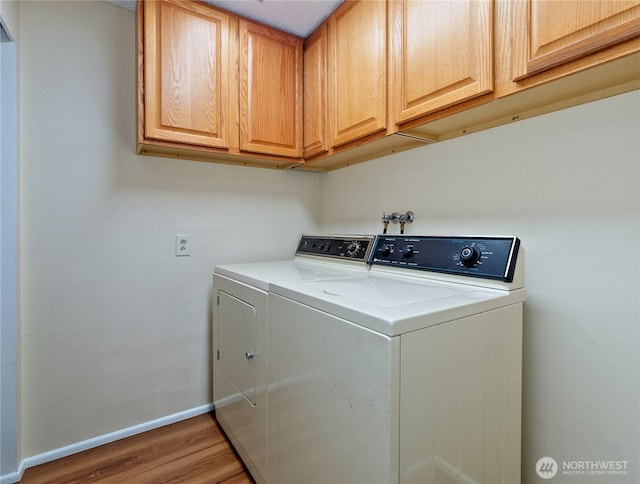 laundry room with cabinet space, washer and dryer, baseboards, and wood finished floors