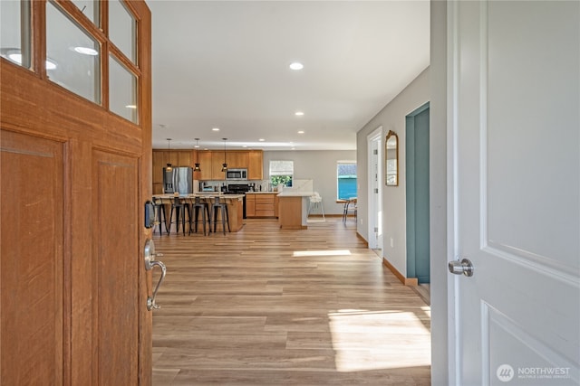 hallway featuring recessed lighting, light wood finished floors, and baseboards