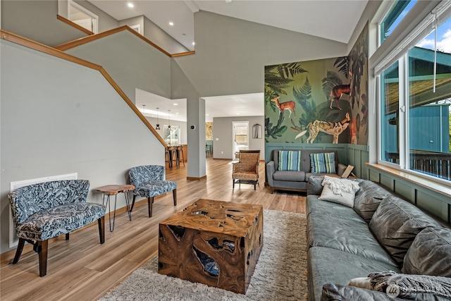 living room with high vaulted ceiling, light wood-type flooring, and recessed lighting