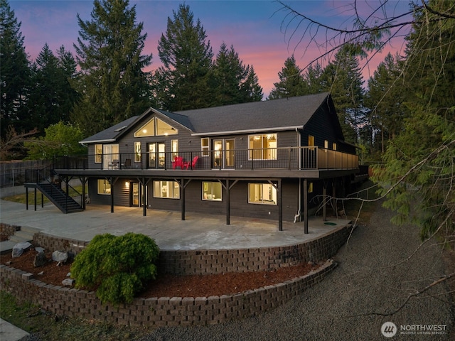 9371 Willamette Meridian Rd NW, Silverdale, WA 98383 - back of house at dusk with stairway, a deck, and a patio