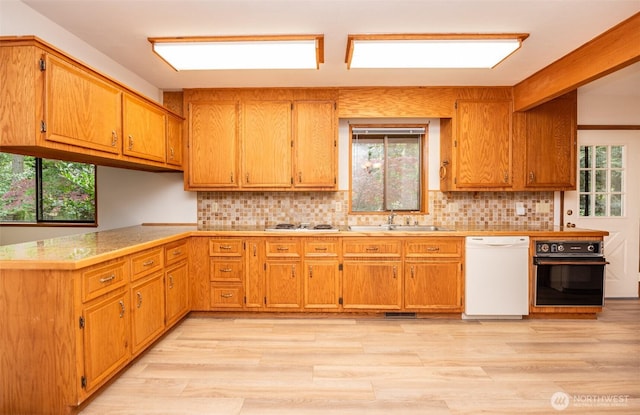 377 Stellar Ridge Ln, Sequim, WA 98382 - kitchen featuring white dishwasher, black oven, a sink, light wood-type flooring, and backsplash