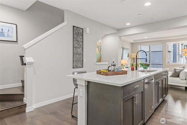 kitchen with a sink, dishwasher, open floor plan, light countertops, and dark wood-style floors