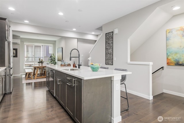kitchen featuring a sink, light countertops, recessed lighting, stainless steel appliances, and a kitchen island with sink