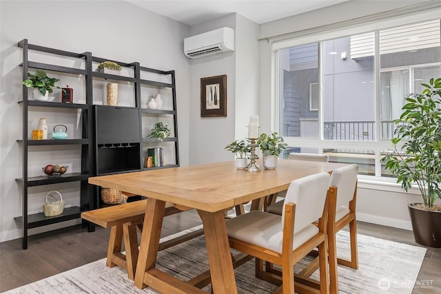 dining room with a wall mounted air conditioner, wood finished floors, and baseboards