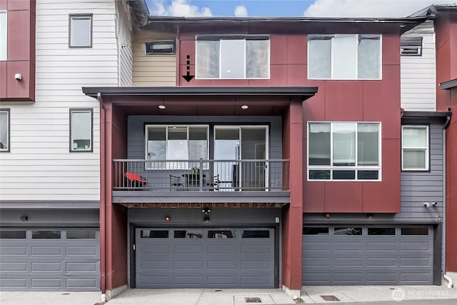 multi unit property with an attached garage, driveway, and a balcony