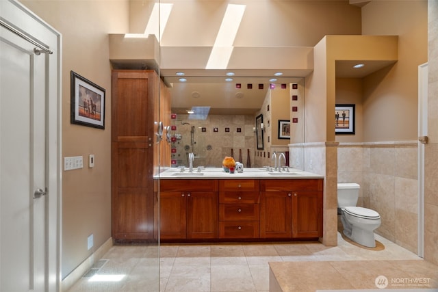 10326 66th Pl W, Mukilteo, WA 98275 - full bath with a skylight, toilet, double vanity, tile walls, and tile patterned floors
