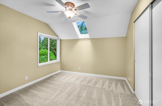 11725 NE 145th St, Kirkland, WA 98034 - carpeted spare room featuring a skylight, baseboards, vaulted ceiling, a textured ceiling, and a ceiling fan