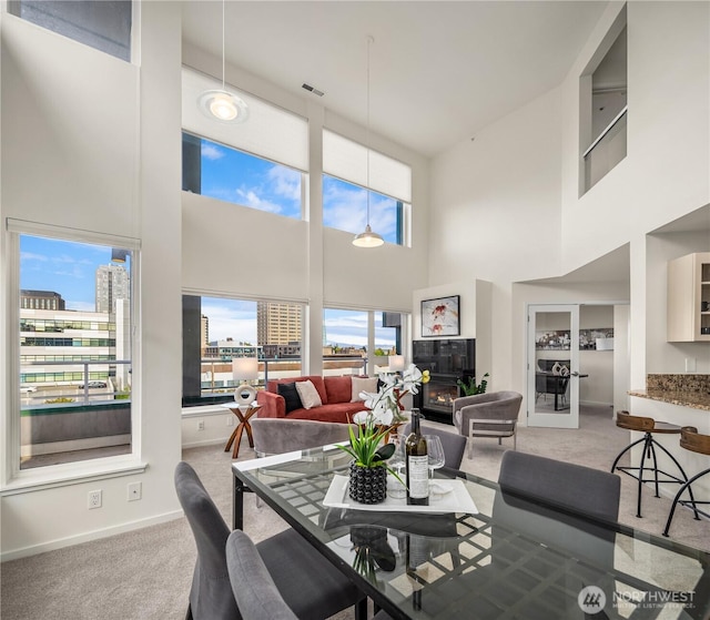 dining room with carpet floors, a high ceiling, baseboards, and a view of city