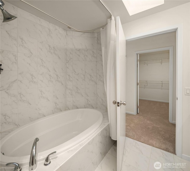 full bathroom with baseboards, shower / bathtub combination with curtain, a skylight, and a spacious closet