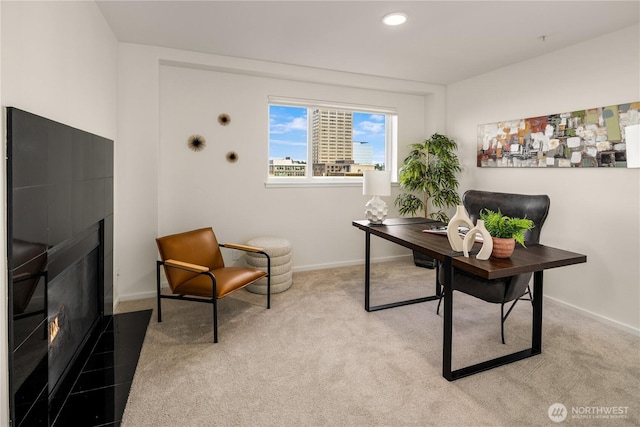 office featuring a glass covered fireplace, light colored carpet, baseboards, and recessed lighting