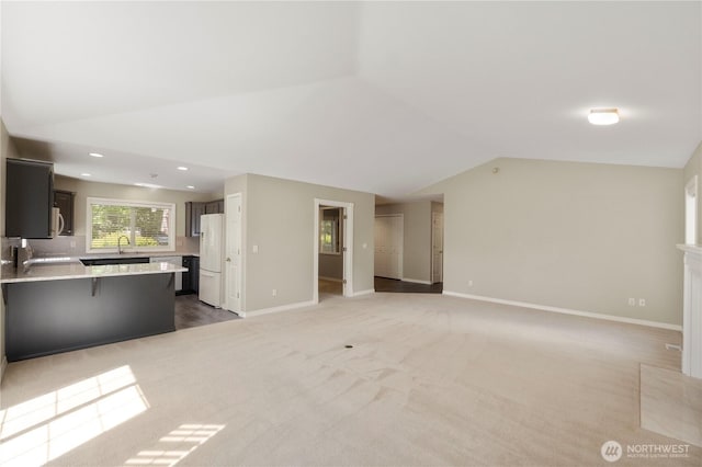 10308 139th Street Ct E, Puyallup, WA 98374 - unfurnished living room featuring lofted ceiling, baseboards, light carpet, recessed lighting, and a sink