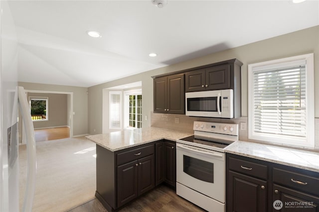 10308 139th Street Ct E, Puyallup, WA 98374 - kitchen with white appliances, vaulted ceiling, tasteful backsplash, a peninsula, and light stone counters
