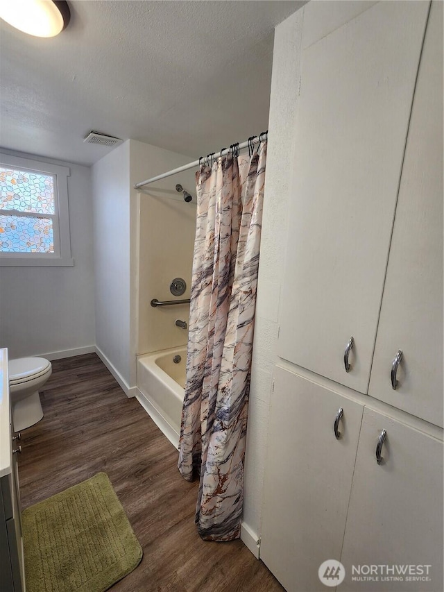 1476 W Sunset Dr, Moses Lake, WA 98837 - full bath with baseboards, wood finished floors, toilet, shower / bath combination with curtain, and a textured ceiling