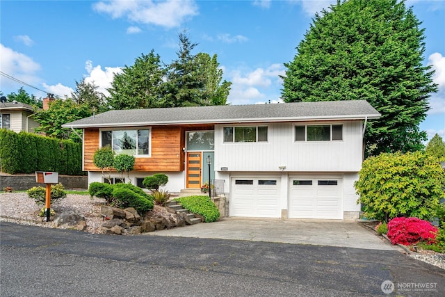 split foyer home featuring a garage, driveway, and a shingled roof