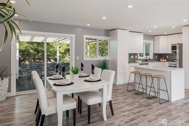 dining space with healthy amount of natural light, light wood-style floors, and recessed lighting