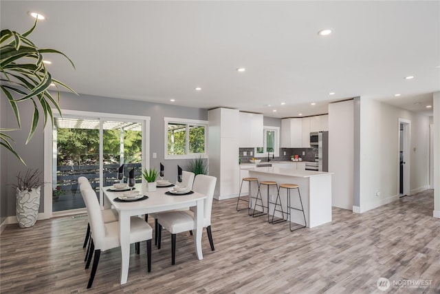 dining room featuring light wood finished floors, recessed lighting, and baseboards