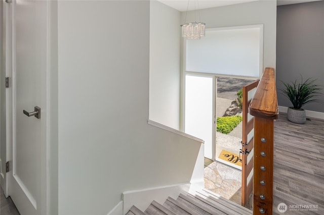 staircase featuring a chandelier, baseboards, and wood finished floors