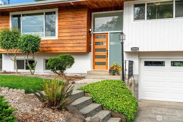 view of exterior entry with brick siding and a garage